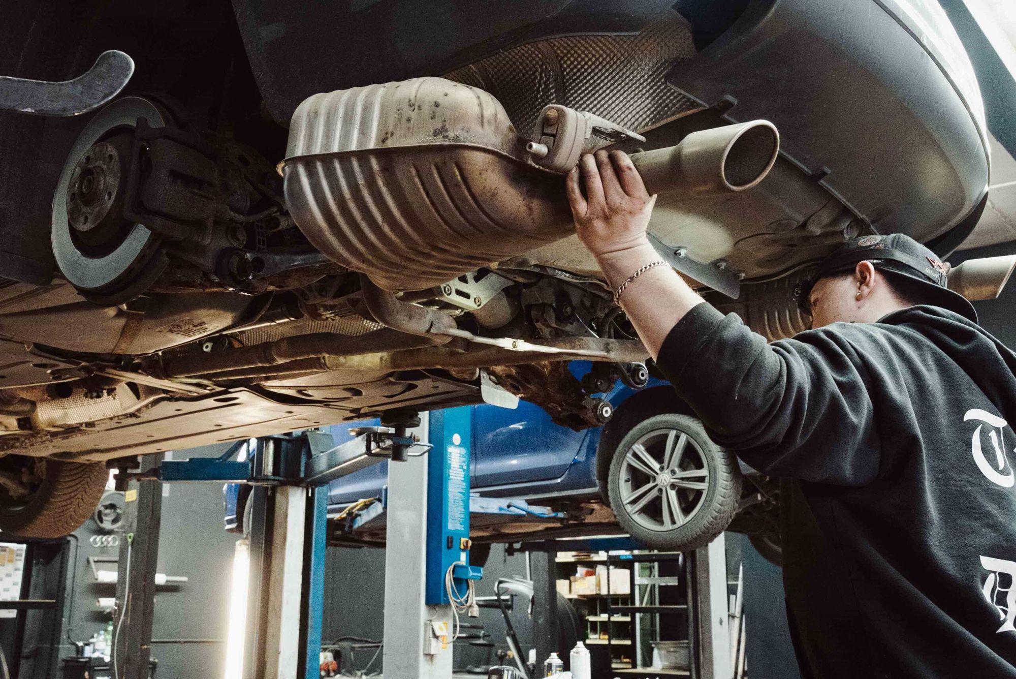 Mechaniker an einer Abgasanlage auf der Hebebühne